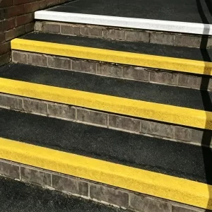 Close-up of yellow fiberglass anti-slip stair nosing installed on metal steps