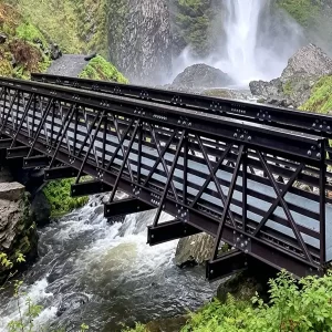 Fiberglass I-beam truss pedestrian bridge spanning waterfall stream