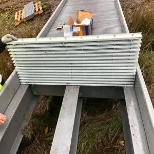 Workers installing FRP grating panels on fiberglass I-beam bridge supports