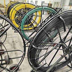 Factory view of FRP rebar production: colored raw material spools and finished composite rebar on production line