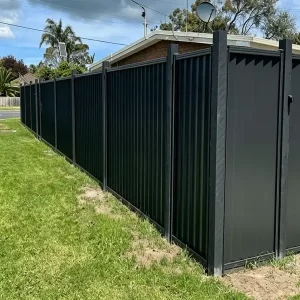 ALT="Dark grey FRP corrugated wall panel Australia style garden privacy fencing with grass ground"