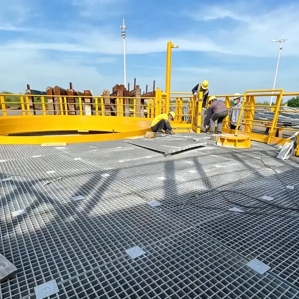 Gray FRP grating platform with yellow safety handrails in an outdoor industrial facility.