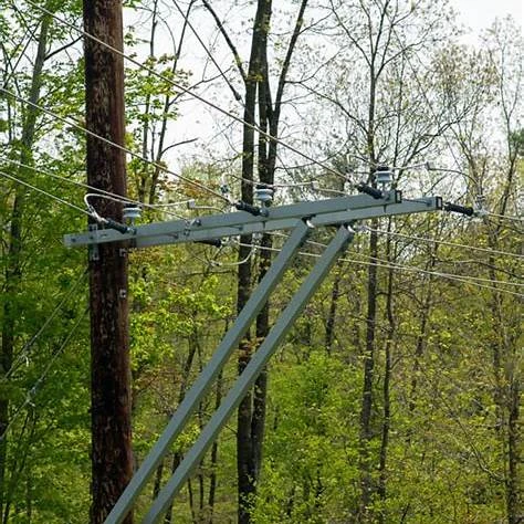 FRP composite cross arm mounted on wooden power pole in dense woodland area with overhead power cables